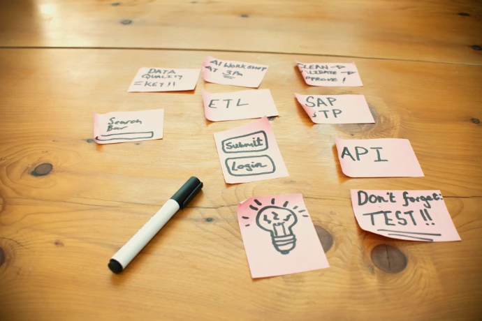 Sticky notes with words and drawings on wooden table.